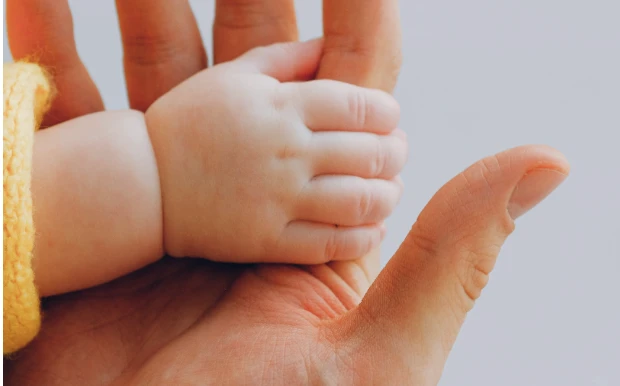 La main d'un bébé tenant le doigt d'un adulte