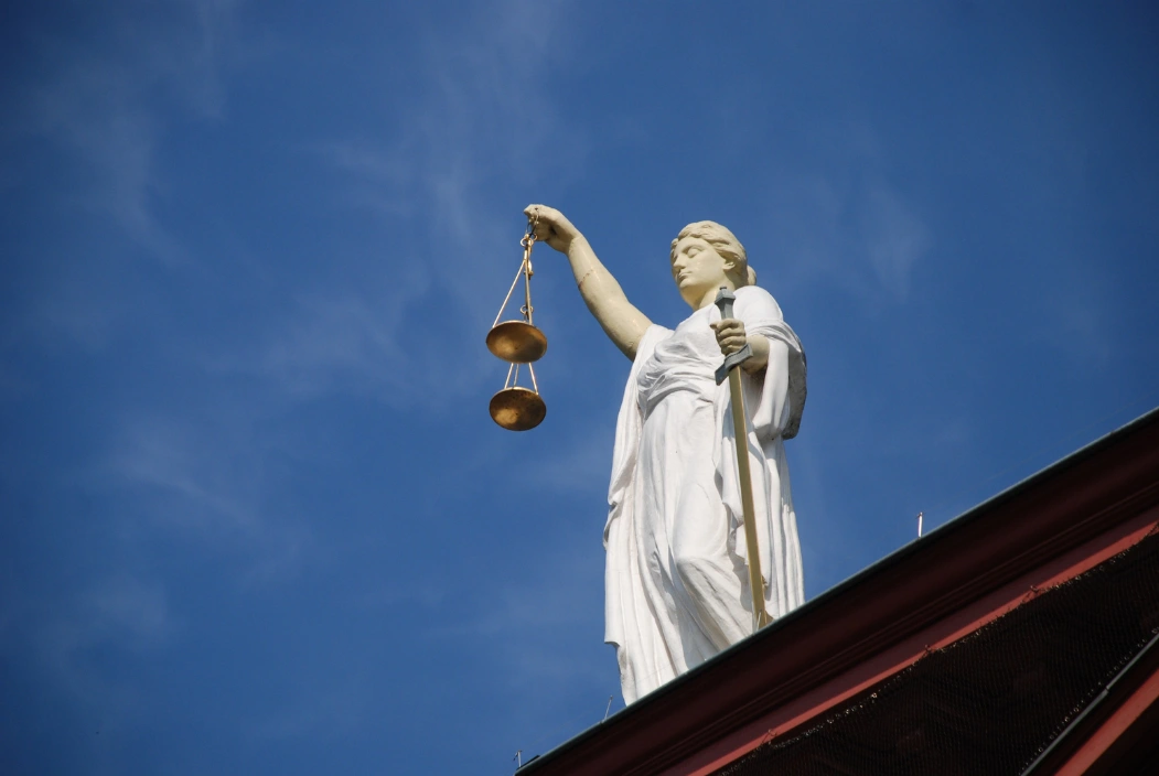 Statue de la Justice tenant une balance sous un ciel bleu